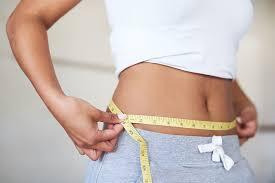 woman with tape measure around her waste, white shirt and white jogging pants