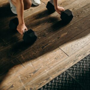 Lady bending down at the knees to pick up a set of 10 pound weights, demonstrating how exercise can improve neuroplasticity. 