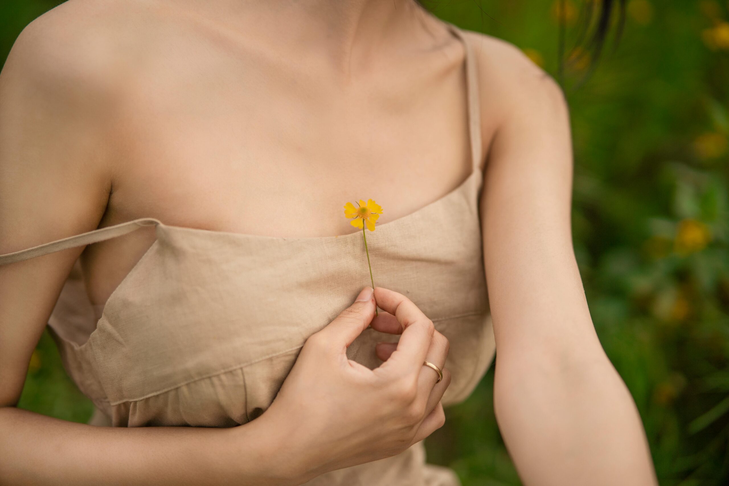 Fair skinned lady with dark hair holding a yellow flower in an article about estrogen and breast cancer