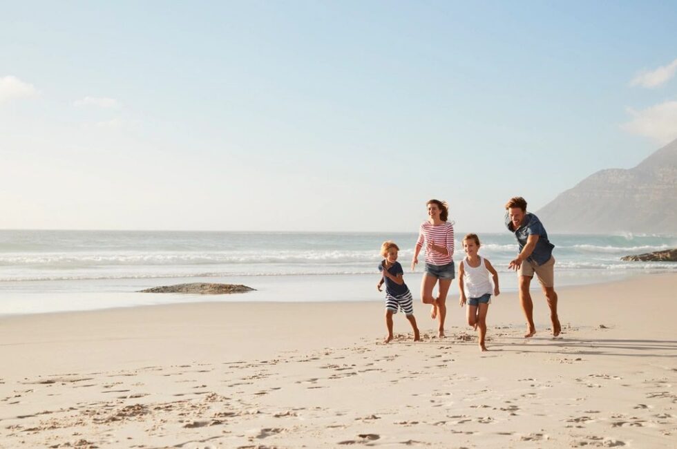 Family of four running on the beach in an article about medicalized motherhood and women's health discussion with practitioner